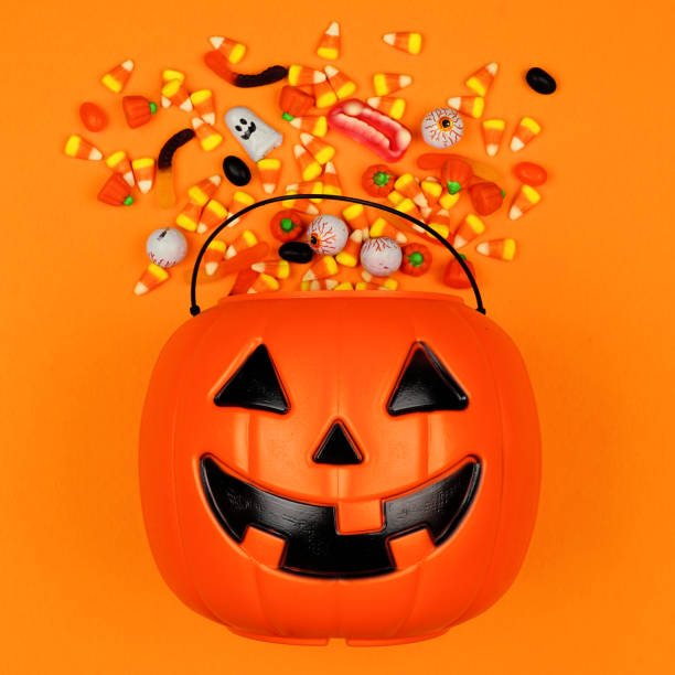 istock Halloween Jack o Lantern bucket with spilling candy, top view on an orange background 1172825186