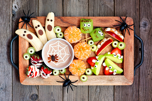 Healthy Halloween fruit snacks. Tray of fun, spooky treats. Top view over a rustic wood background.