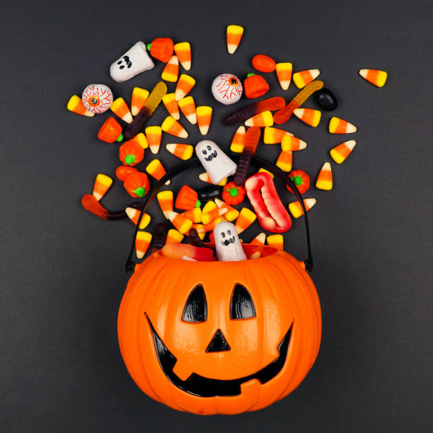 istock Halloween Jack o Lantern pail with spilling candy, top view on a black background 1172825777