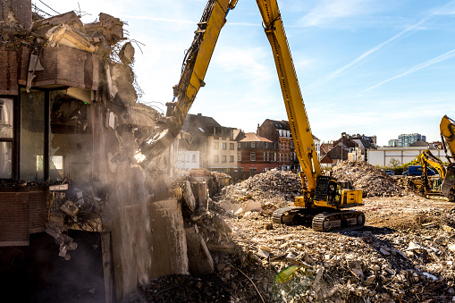 Demolition of a building in progress with a huge machine. Hydraulic Crusher excavator machine at demolition on construction site