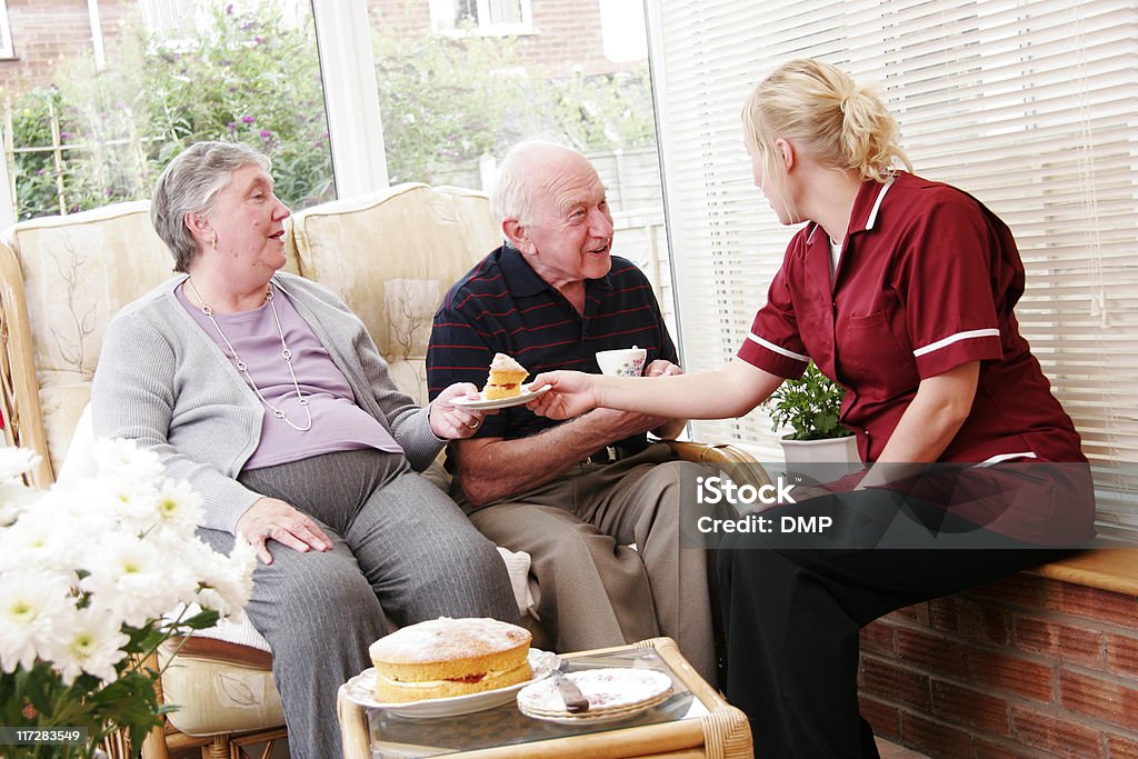 Feliz pareja senior a joven enfermera en el cuidado de su hogar - Foto de stock de Actividad libre de derechos