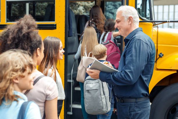 istock Classmates going into school bus while driver checking attendance smiling happy close-up 1172836908