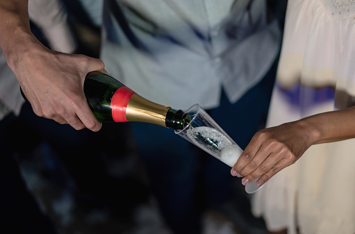 Close-up on a man pouring champagne at the nightclub - drinking concepts