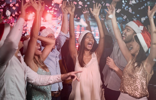 Excited group of people at a nightclub celebrating Christmas partying and dancing