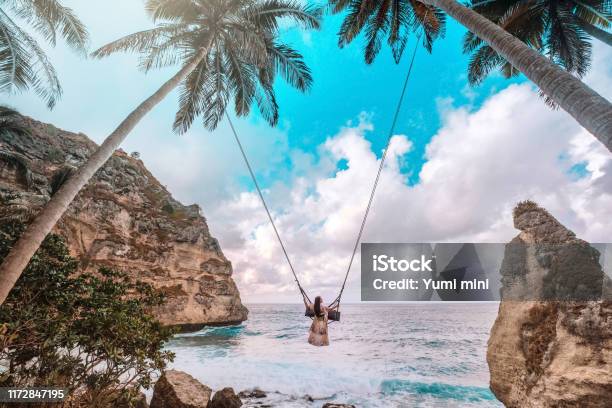 Beautiful Girl On Swing Coconut Palms On Beach At Daimond Beach Nusa Penida Island Bali Indonesia Stock Photo - Download Image Now