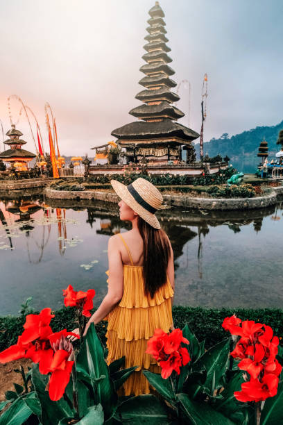 азиатская женщина путешествие в пура улун дану бератан плавучий храм на бали , индонезия утром. - travel destinations vacations exoticism beauty in nature стоковые фото и изображения