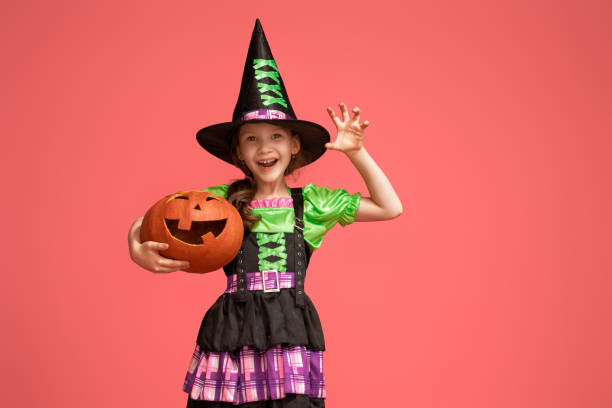 istock little witch with a pumpkin on pink background 1172852133