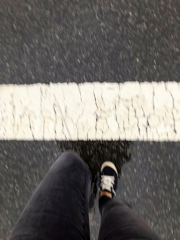 Looking down, walking across a rainy crosswalk in New York City.