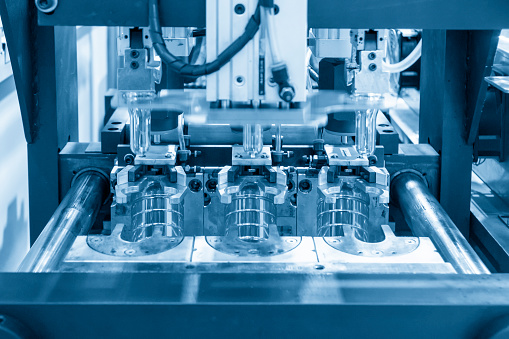 La operación del molde de soplado de botellas de PET de agua potable procesamiento de fabricación de contenedores en la escena azul claro. photo