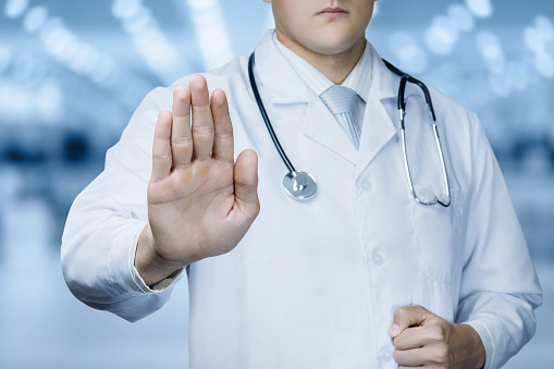 Doctor with forbidden gesture of the hand on a blurred background.