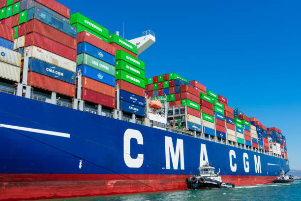 タグボートは、青空の下でオークランド港でフランスのコンテナ船cma cgmを支援します - oakland california commercial dock harbor california ストックフォトと画像