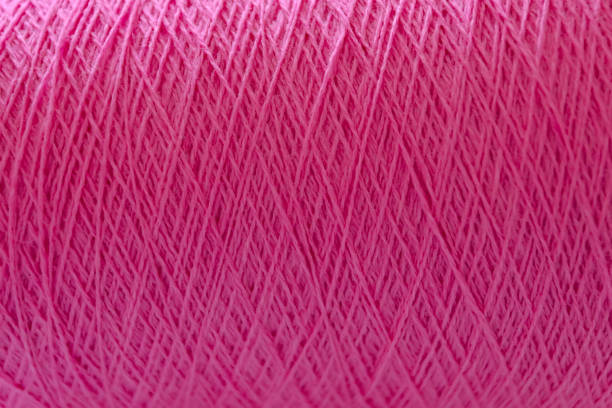 istock Close Up of thread wound on spool. Fuchsia color background 1172868699