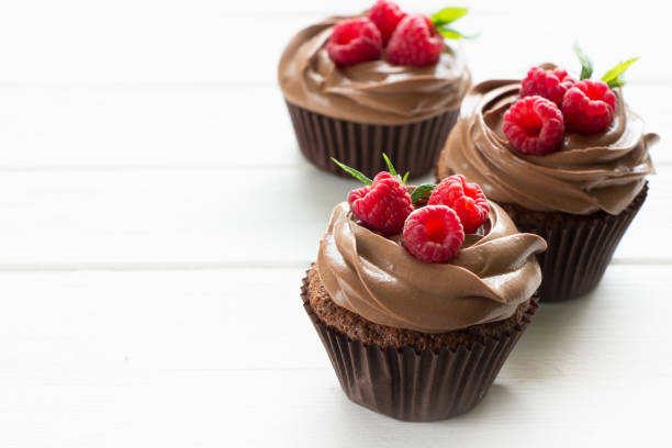 istock Chocolate cupcakes with fresh raspberries , white background 1172875903