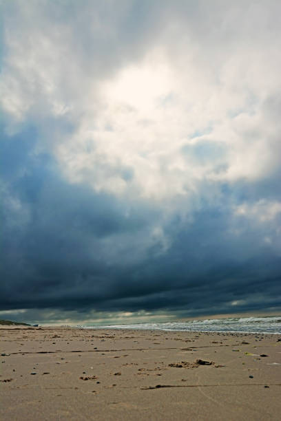 istock Dark blue stormy clouds with sun shining through at beach 1172877130