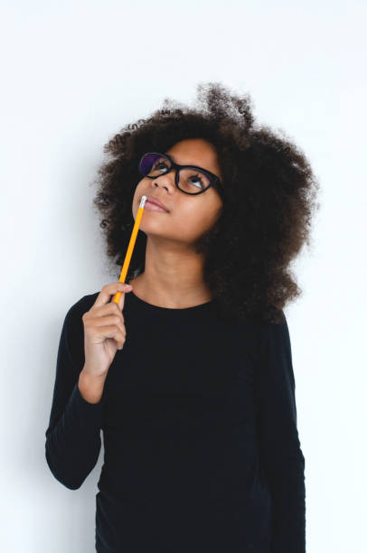 istock A dark-skinned girl thought for a moment, leaning a pencil on her lips. 1172878083