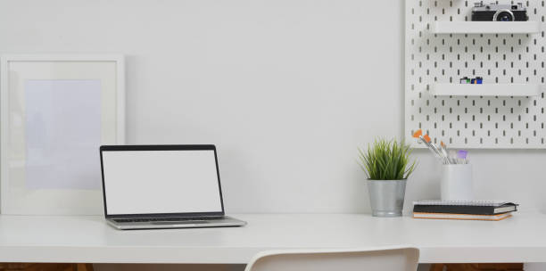 istock Open blank screen laptop computer with copy space and office supplies in minimal office room 1172881153