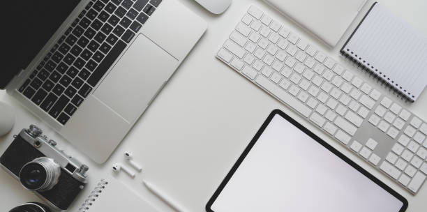 istock Top view of modern workplace with laptop computer, camera, tablet, office supplies on white desk background 1172881174