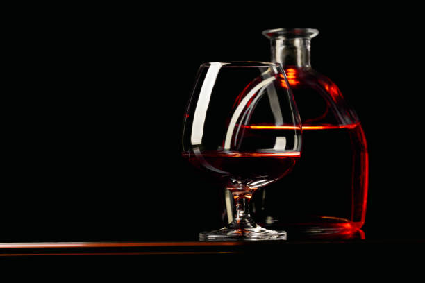 Glass and bottle of brandy on a black background.