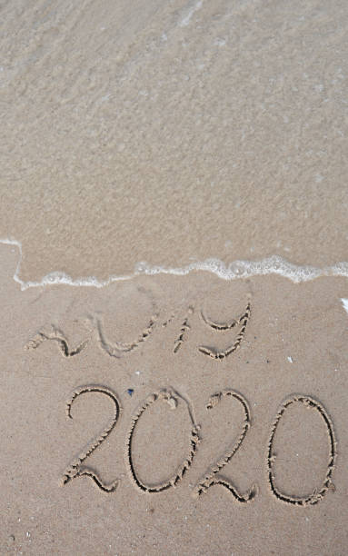 istock Vertical New Years 2020 replace 2019 concept. Handwritten inscription 2019 and 2020 on beautiful sand beach. End of 2019 Happy New Year 2020, lettering on beach with wave and clear blue sea. 1172882744