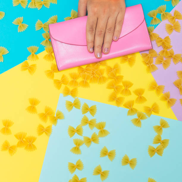 istock Hand holds pink purse or wallet among pasta bows on geometric background 1172884754
