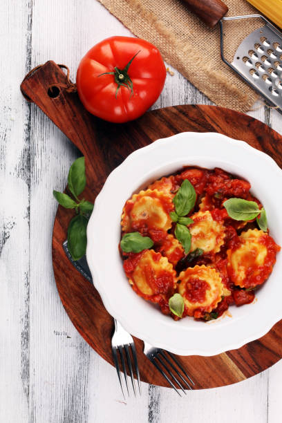 istock Ravioli with tomato sauce garnished with parmesan cheese and basil on rustic table 1172886683