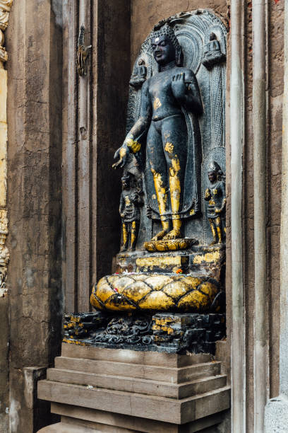 fermez-vous vintage bronze lord bouddha statue bâton avec de petits papiers d'or en face du temple de mahabodhi qui voient d'en bas tout en pleuvant à bodh gaya, bihar, inde. - bodhgaya architecture image human age photos et images de collection