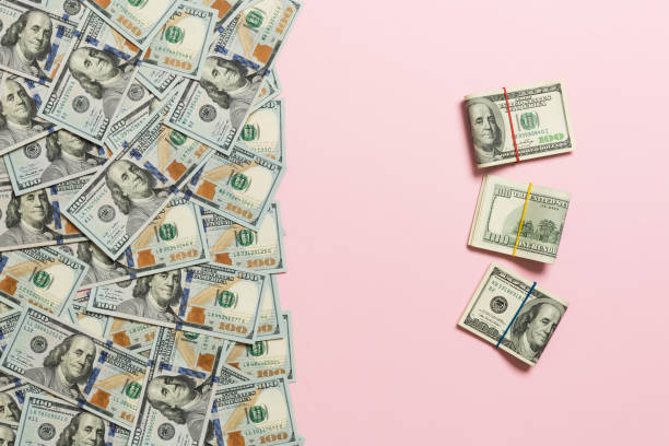 istock dollars currency on colored background top view, with empty place for your text business money concept. One hundred dollar bills with stack of cash 1172896552
