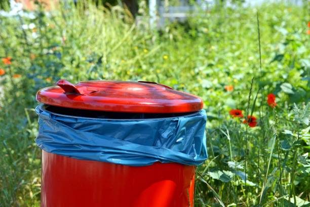 istock red trash bin on footpath and a green area with blank space. waste bins on curb with copy space sign. recycling concept. 1172897042