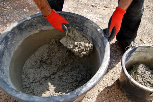 istock Foundation and form work. Male worker hands are mixing concrete in a bucket at a construction site. Mixing Cement or mortar with Electric drill with a mixer. 1172900164
