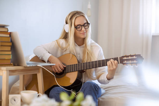 Girl Playing Guitar at Home stock photo