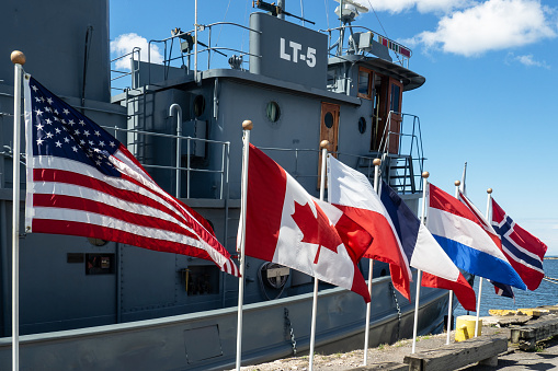 Oswego, New York, USA. September 6, 2019. Country flags in front of  the World War II tug boat the LT-5 on display at the H. Lee White Maritime Museum in downtown Oswego on the shores of Lake Ontario