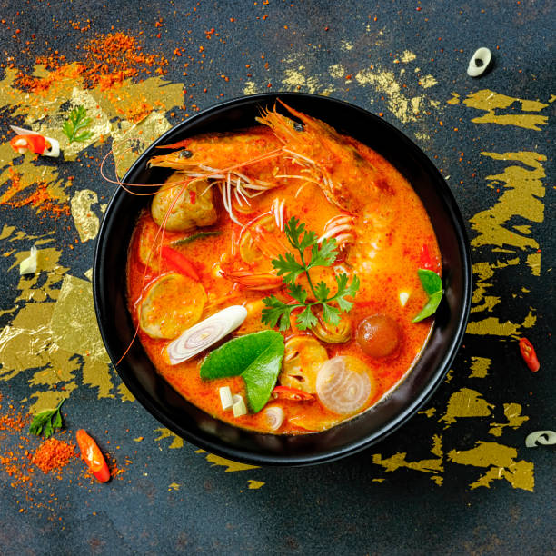 thailand's famous rich, red, coconut milk based, delicious tom yam kung soup in a bowl on an abstract background. - sopa tom yum imagens e fotografias de stock