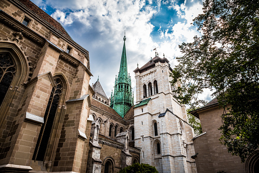 Color image depicting the ancient cathedrals and churches amid the old town traditional architecture of Geneva, Switzerland. The buildings are offset by a dazzling blue sky and cloudscape. Room for copy space.