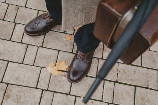 istock Men legs in leather shoes on concrete tile top view 1172903877