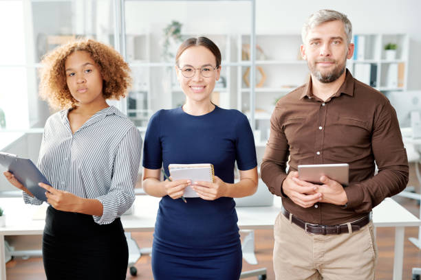 istock Young contemporary co-workers standing in line in front of camera 1172904689