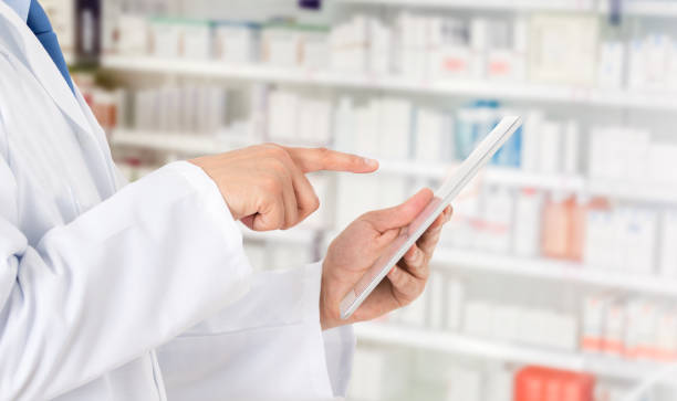 pharmacien prenant des notes sur une tablette numérique - pharmacist pharmacy pill medicine photos et images de collection