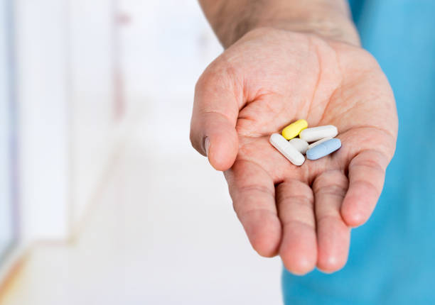 istock man's hand holding out some white pills 1172906763