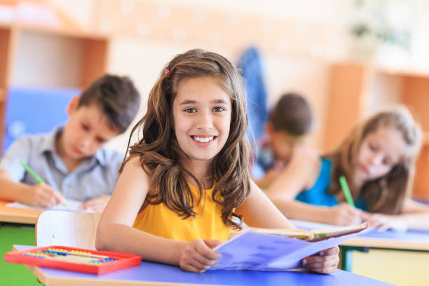 istock Schoolgirl reading a book in the classroom 1172910666