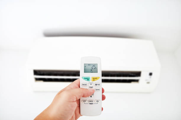 istock Modern Air conditioner unit with a hand holding a remote. 1172910949