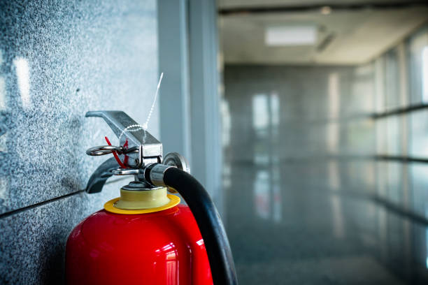 close up of fire extinguisher. interior of building in public place. the subject is on the left. - department store shopping mall store inside of imagens e fotografias de stock