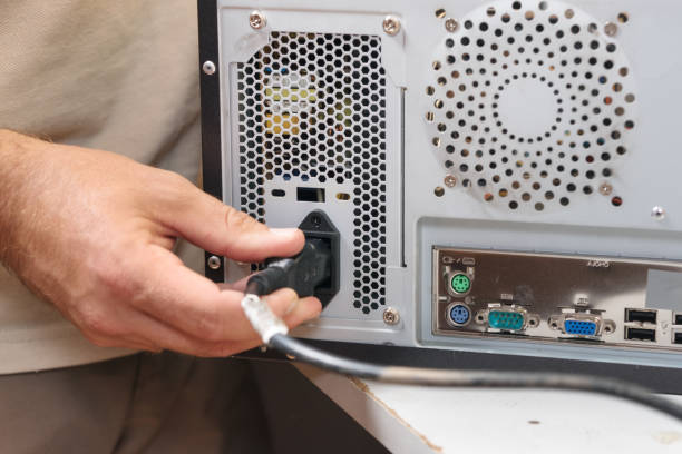 man hand inserts power cord into a computer. - electric plug outlet human hand electricity imagens e fotografias de stock