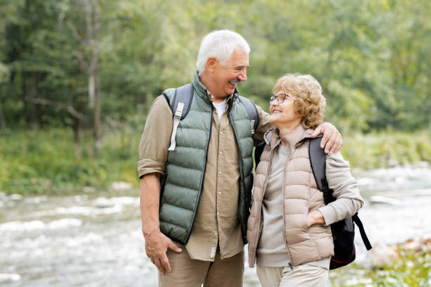 istock Two cheerful mature backpackers looking at one another in natural environment 1172918127