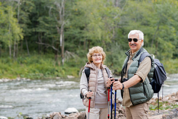 istock Active aged spouses with backpacks and trekking sticks enjoying summer trip 1172918162