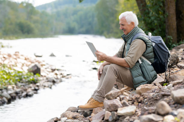istock Mature backpacker with touchpad using video chat to communicate with his wife 1172918192