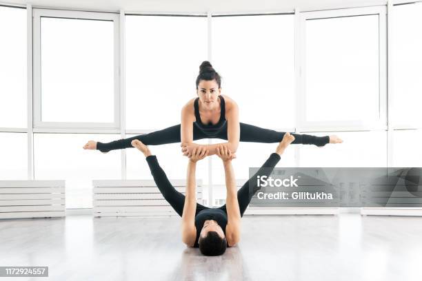 Young Couple Doing Acro Yoga In Pair At Studio Stock Photo - Download Image Now - Acroyoga, 30-34 Years, Acrobatic Activity