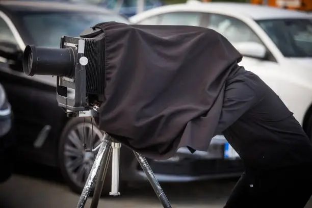 Close up shot of a photographer using a vintage camera on a tripod.