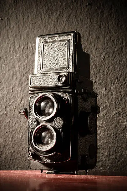 Old camera in front of an black wall.