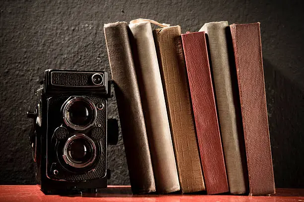Old camera and old books on bookshelf.