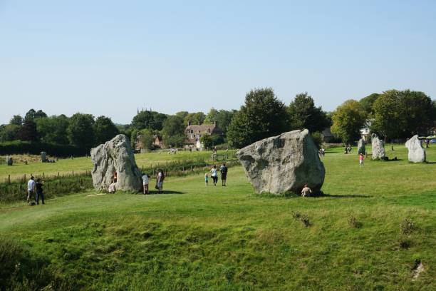 Tourists at Avebury Henge Tourists explore the largest stone circle momument in the world located in the North Wessex Downs, Wiltshire, southern England. stone age stock pictures, royalty-free photos & images