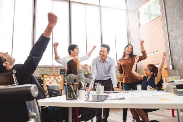 gli uomini d'affari sorridono e alzano le mani, si sentono felici, completano il lavoro di finitura, il lavoro di squadra ha successo / si è svolto lavorando nel concetto di ufficio - happiness cheerful business person variation foto e immagini stock